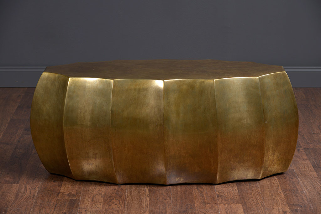 A large, contemporary coffee table with a scalloped design and an antiqued brass finish.