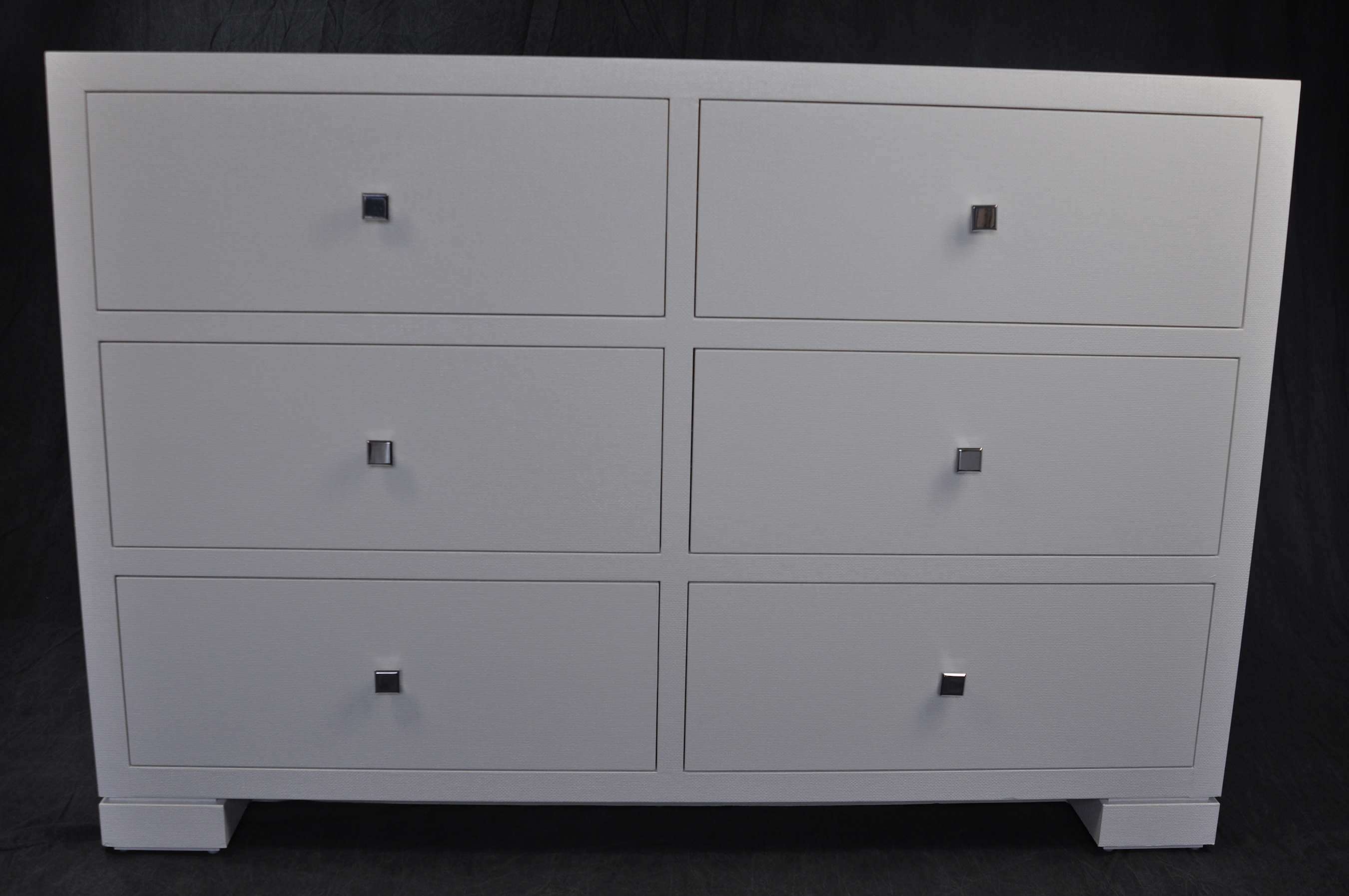 White six drawer dresser with hand-cast chrome handles, showcasing a clean and modern design.