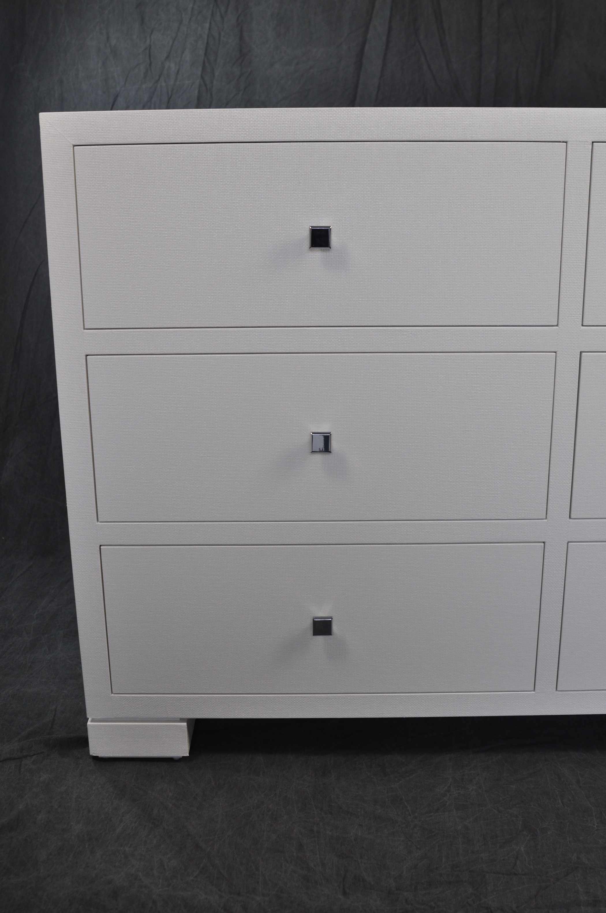 White six drawer dresser with hand-cast chrome handles, displayed in a showroom.