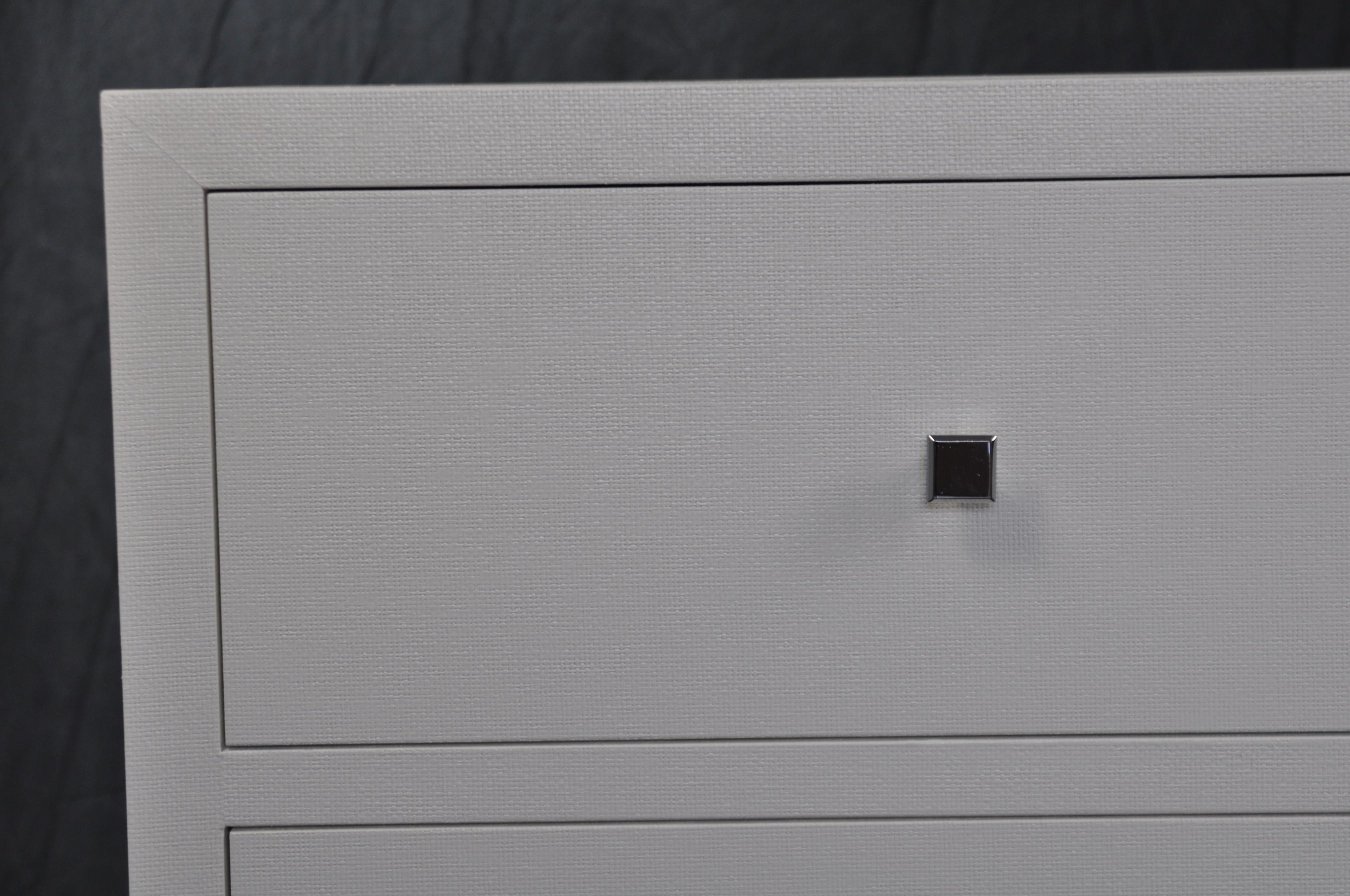 White six drawer dresser with a single visible handle, set against a dark background.