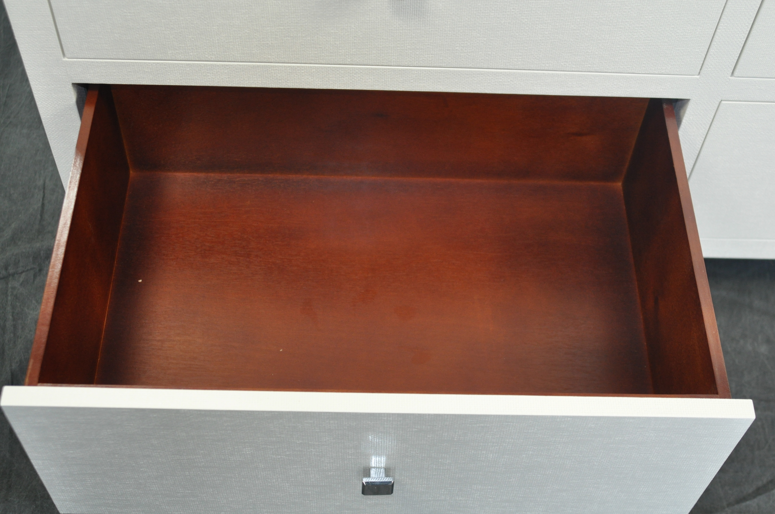 A large, six-drawer dresser with a white lacquered finish and chrome handles, displayed in an open position against a dark background.