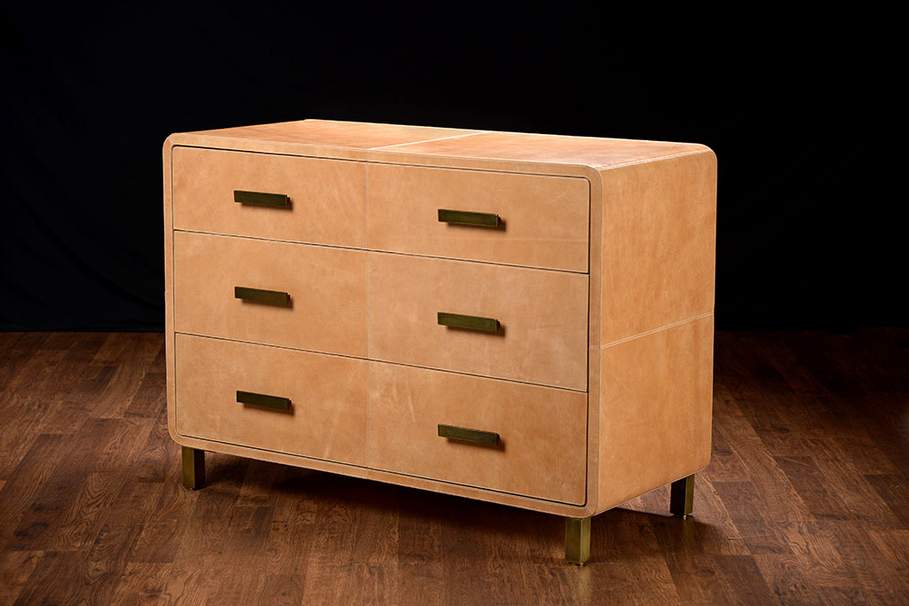A large rectangular leather dresser with curved edges and three drawers The dresser is made from highly distressed rustic leather in a