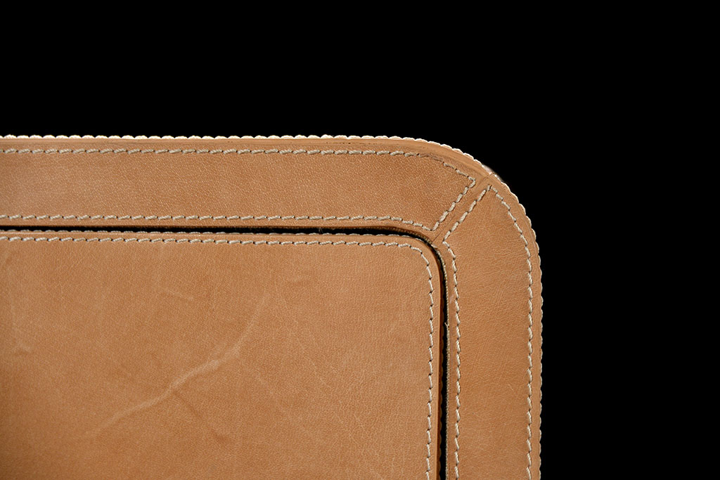 Brown leather dresser with curved edges and three drawers, showcasing its natural cowhide texture and rustic appearance.