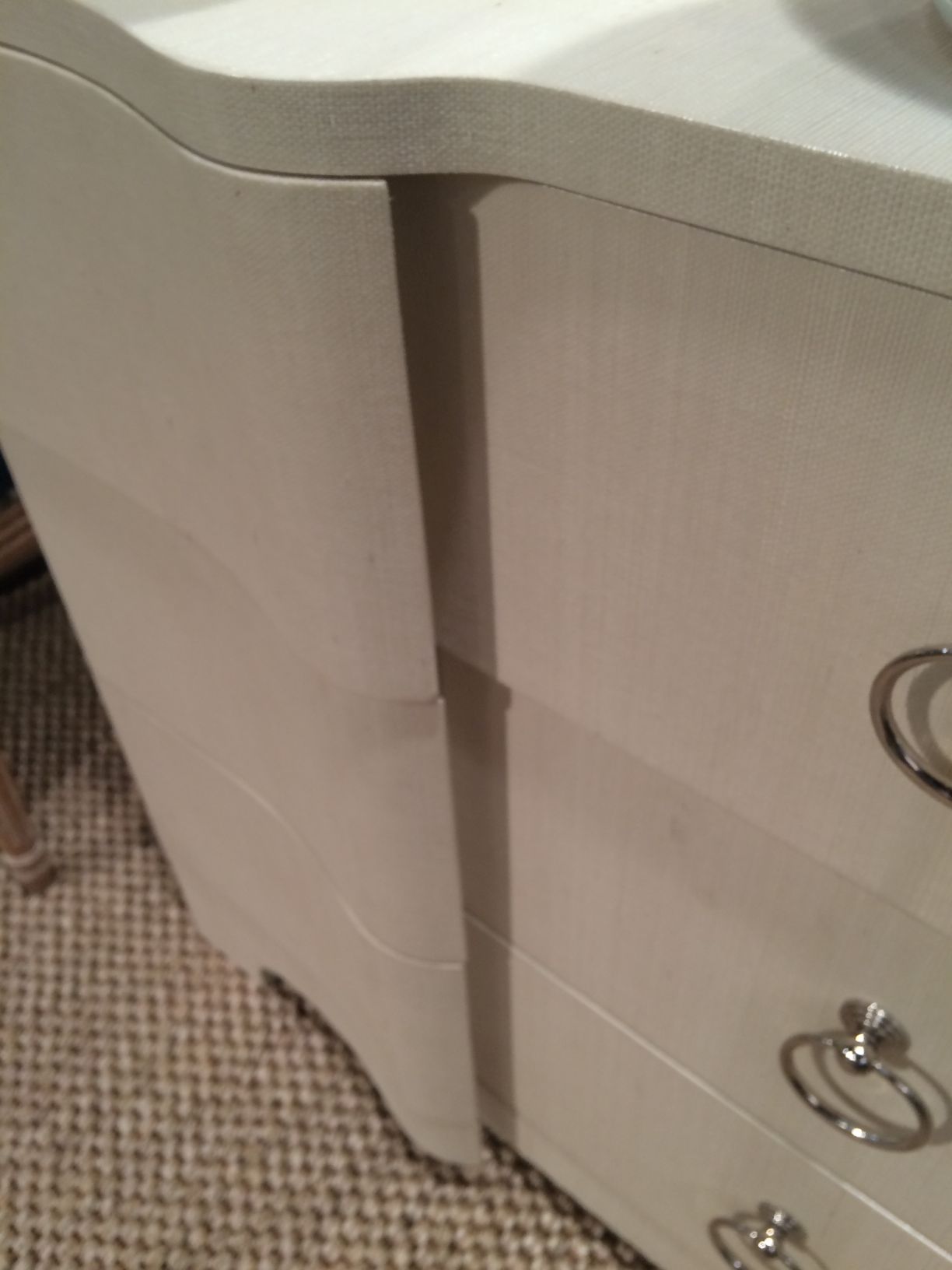 White dresser with a curved front and silver ring pulls.