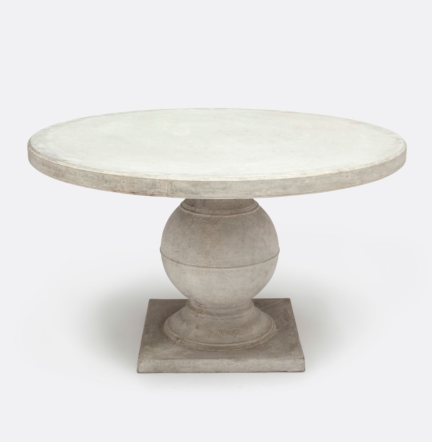 Round concrete dining table with a light gray finish, set against a white background.