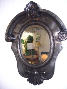 A wall mirror with an ornate, carved metal frame in a French grey finish.
