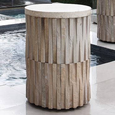 An outdoor round stone top coffee table with hand chiseled sculpted sides.