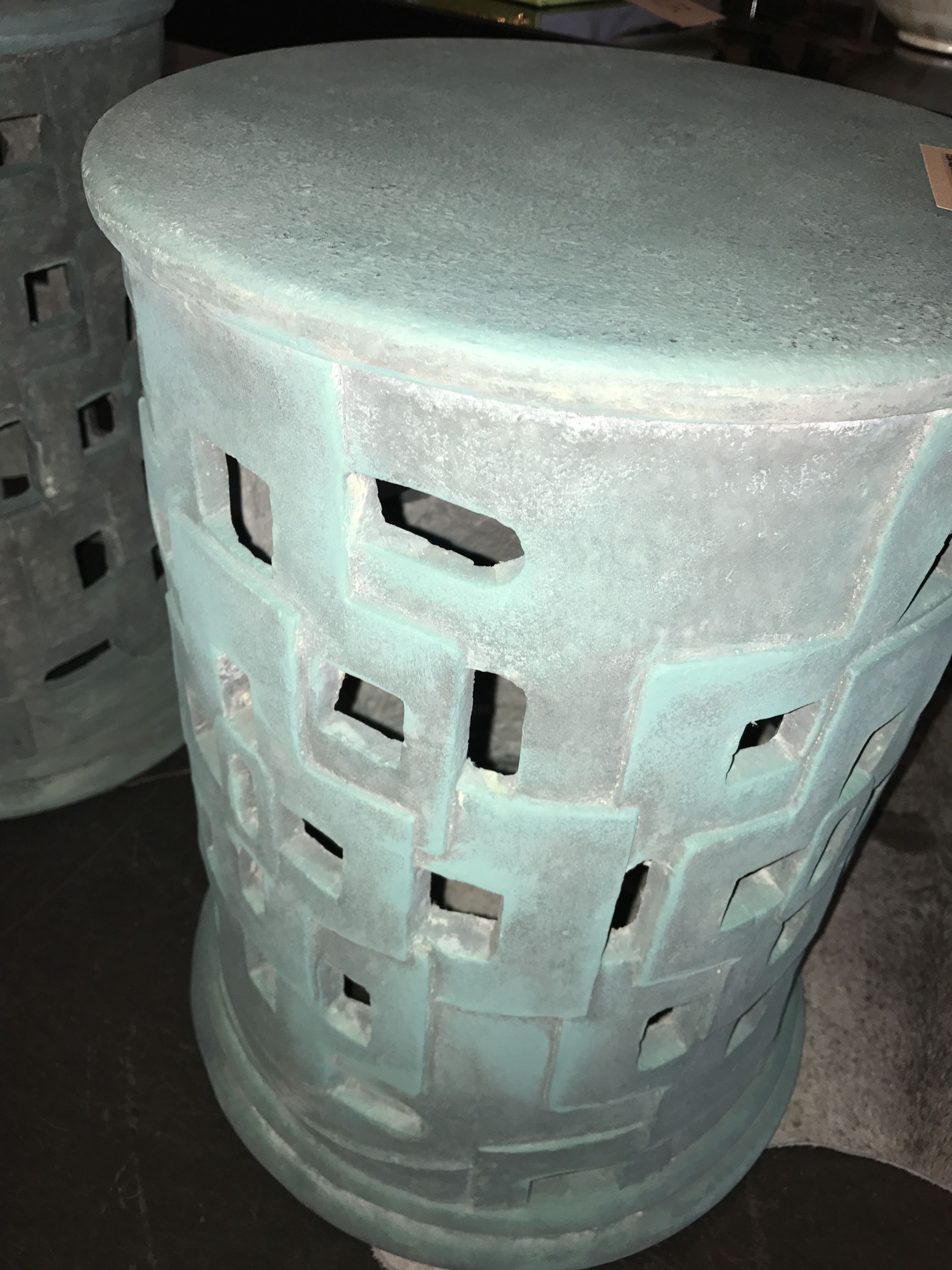 A handcrafted outdoor patched cut out concrete stool with minor cracks and imperfections, available in light grey or verdigris.