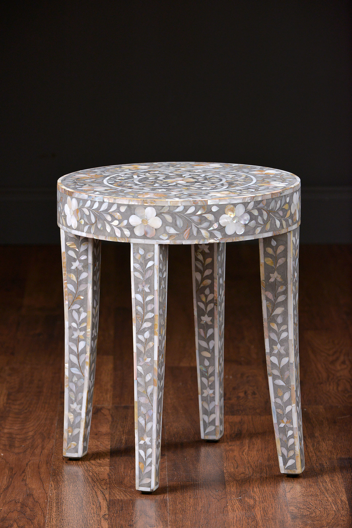 A small, decorative side table with a unique design featuring inlaid mother of pearl and resin elements.