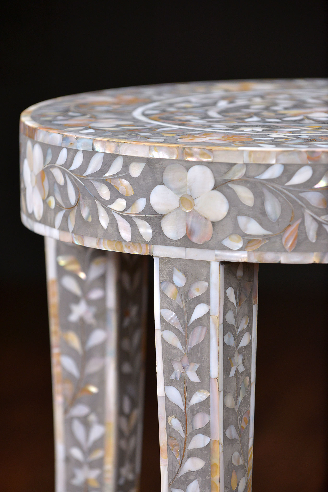 A decorative side table with a mother of pearl inlay design, showcasing intricate patterns on its surface.