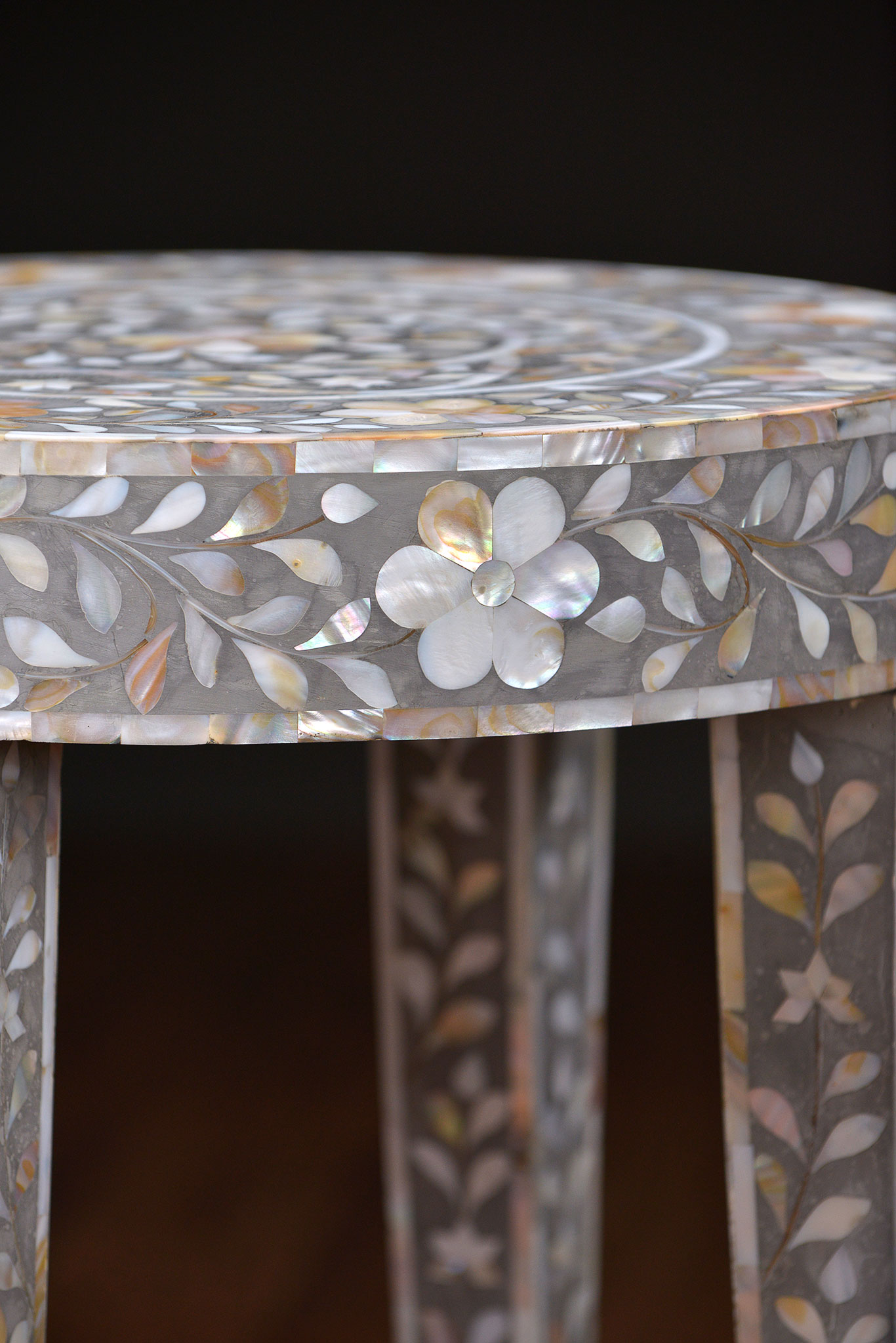 A decorative side table with a marbled, grey and white mother of pearl inlay design on a wooden base.