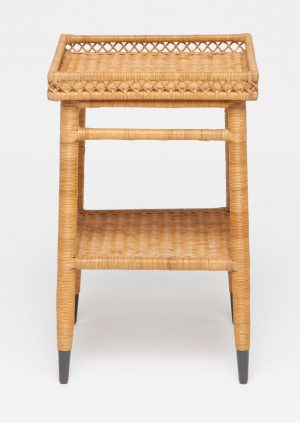Small wicker side table with intricate patterns, black legs and a rectangular top.