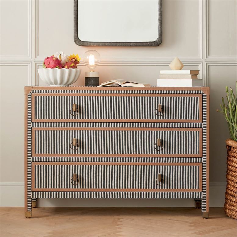 A decorative dresser with a navy and cream canvas stripe design featuring three drawers and camel leather trim set against a white